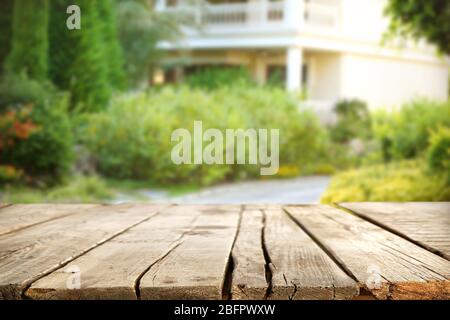 Leerer Holztisch und schöner Garten im Hintergrund Stockfoto