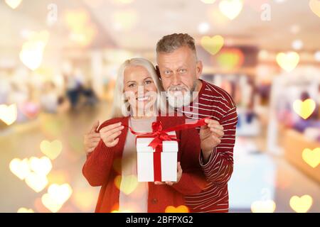 Senior glücklich paar mit Weihnachtsgeschenk auf verschwommenem Hintergrund Stockfoto