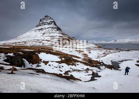 Kirkjufell Berg mit Schnee bedeckt mit Touristen in der verschneiten Landschaft, Grundarfjordur, Snaefellsnes Halbinsel, Island Stockfoto