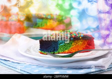 Teller mit Stück Regenbogenkuchen auf dem Tisch Stockfoto