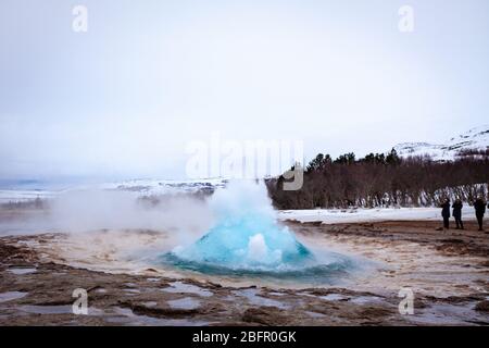 Geysir, Island - Strokkur heiße Quelle im Geysir Geothermie-Gebiet bricht an einem bewölkten Tag im Winter aus Stockfoto