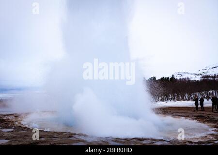 Geysir, Island - Strokkur heiße Quelle im Geysir Geothermie-Gebiet bricht an einem bewölkten Tag im Winter aus Stockfoto