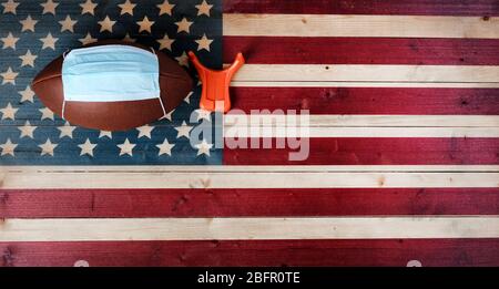 American Football mit chirurgischer Schutzmaske und Kicking T-Shirt auf Vintage United States Holzfahne Hintergrund. Coronavirus Konzept für Affect footba Stockfoto