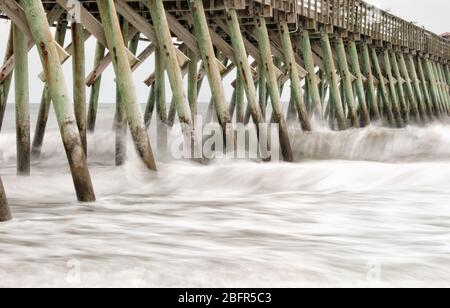 Lange Kameraaufnahme erfasst hohe abstürzende Wellen des Atlantischen Ozeans auf einem Pier in Myrtle Beach South Carolina. Stockfoto