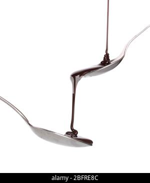 Die Schokolade hat in den Löffel und von ihm zu einem anderen Löffel auf weiß isoliert gegossen Stockfoto