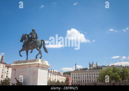 ROI Louis XIV Statue auf dem Place Bellecour Platz, in der Innenstadt von Lyon, mit der Basilique Notre Dame de Fourviere Kirche im Hintergrund im Sommer. pict Stockfoto