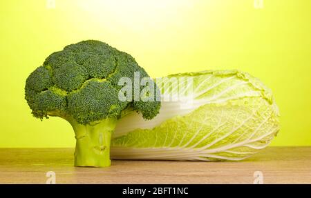 Frischer Brokkoli und chinakohl auf Holztisch auf grünem Hintergrund Stockfoto