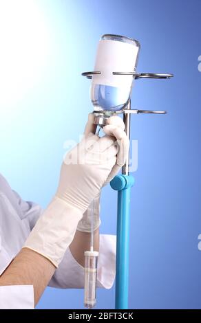 Krankenschwester, die Infusion auf blauem Hintergrund macht Stockfoto