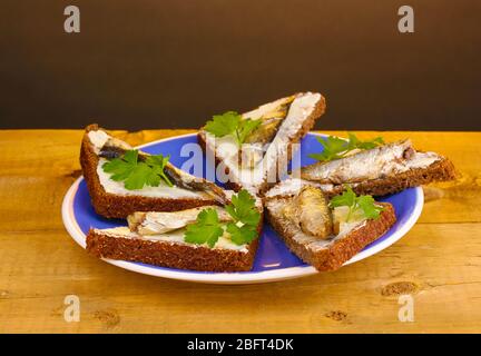 Leckere Sandwiches mit Sprossen auf Teller auf Holztisch auf braunem Hintergrund Stockfoto