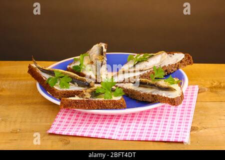 Leckere Sandwiches mit Sprossen auf Teller auf Holztisch auf braunem Hintergrund Stockfoto