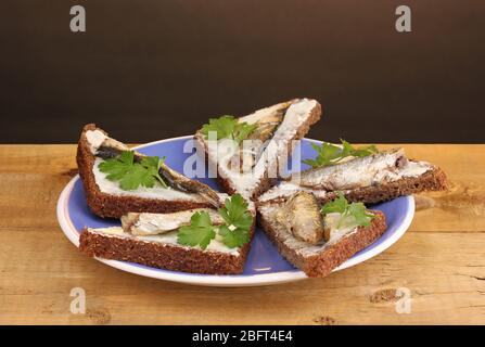 Leckere Sandwiches mit Sprossen auf Teller auf Holztisch auf braunem Hintergrund Stockfoto