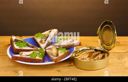 Leckere Sandwiches mit Sprossen auf Teller auf Holztisch auf braunem Hintergrund Stockfoto