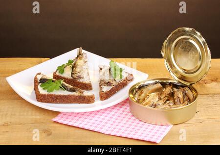 Leckere Sandwiches mit Sprossen auf Teller auf Holztisch auf braunem Hintergrund Stockfoto