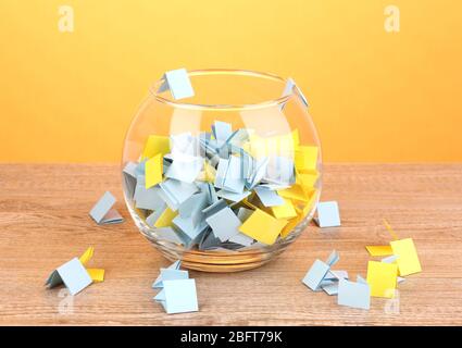 Stücke Papier für Lotterie in Vase auf Holztisch auf gelbem Hintergrund Stockfoto