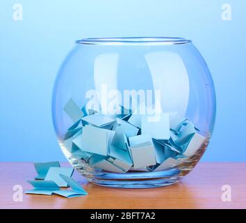 Stücke Papier für Lotterie in Vase auf Holztisch auf blauem Hintergrund Stockfoto
