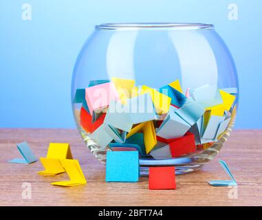 Stücke Papier für Lotterie in Vase auf Holztisch auf blauem Hintergrund Stockfoto