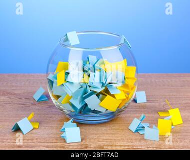 Stücke Papier für Lotterie in Vase auf Holztisch auf blauem Hintergrund Stockfoto