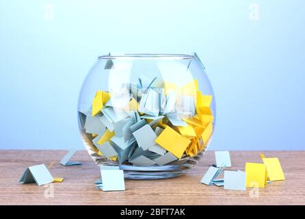 Stücke Papier für Lotterie in Vase auf Holztisch auf blauem Hintergrund Stockfoto