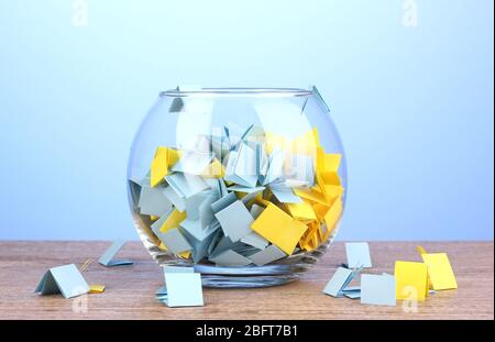 Stücke Papier für Lotterie in Vase auf Holztisch auf blauem Hintergrund Stockfoto