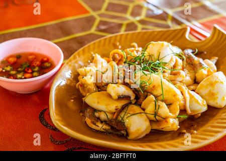 Im Rührteig gebratener Tintenfisch mit gekochtem, gesalzenem EnteneierEigelb in einer braunen Schüssel auf einem Tisch. Stockfoto