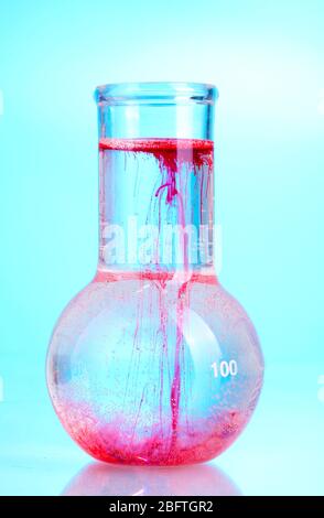 Helle Tinte in einer Flasche mit Wasser auf blauem Hintergrund Stockfoto