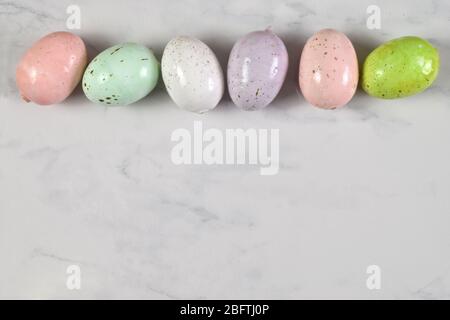 Von oben nach unten Blick auf bunte gesprenkelte Ostereier auf einem Marmorhintergrund. Enthält einen optionalen Clipping-Pfad um die Ostereier. Stockfoto