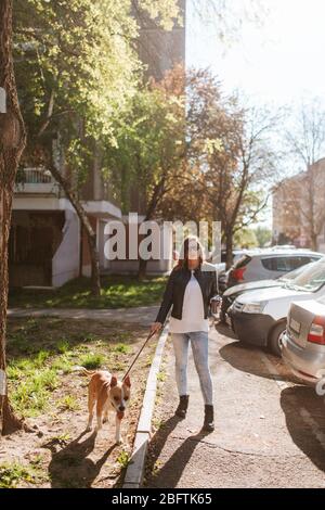 Eine schöne kaukasische Frau mit einem Hund Rasse American Staffordshire Terrier läuft die Straße hinunter Stockfoto