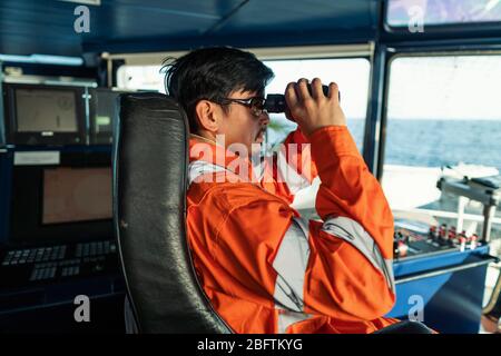 Philippinische Deck Officer auf Brücke des Schiffes oder Schiff Blick durch Fernglas Stockfoto