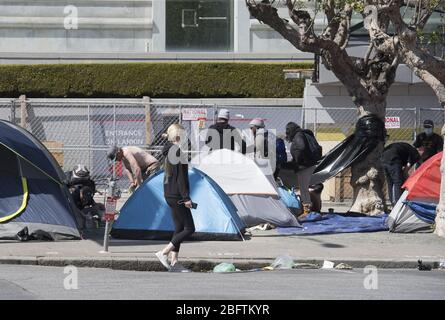 San Francisco, Usa. April 2020. Ein maskierter Fußgänger passiert am Sonntag, den 19. April 2020, ein obdachloses Lager im Bürgerzentrum von San Francisco. San Francisco Mayor London Rasse sagt, dass efective jetzt, Gesichtsmasken müssen außerhalb des Hauses getragen werden, um vor Coronavirus zu schützen. Foto von Terry Schmitt/UPI Quelle: UPI/Alamy Live News Stockfoto