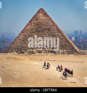 Touristen Reiten Kamele zu einer Pyramide in Gizeh, Ägypten Stockfoto