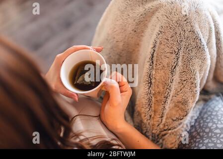 Draufsicht auf kranken kaukasischen Mädchen mit Maske trinken Tee Im Bett während COVID - 19 Coronavirus Stockfoto
