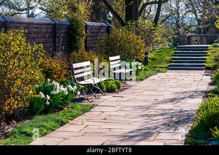 Ein Gehweg in einem Garten mit hölzernen Parkbänken im Mellon Park, einem Park, der der Stadt Pittsburgh, Pennsylvania, USA gehört und gepflegt wird Stockfoto