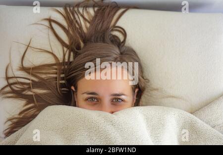 Frau im Bett bis ins Gesicht bedeckt Stockfoto