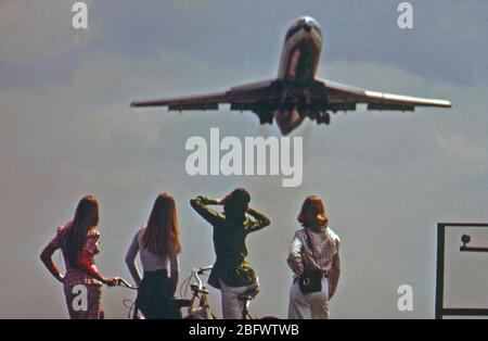 Eines der Radfahrer hält ihre Ohren gegen das Brüllen des Jets abheben vom nationalen Flughafen, Mai 1973 Stockfoto