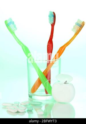 Zahnbürste aus Glas, Zahnseide und Kaugummi auf grünem Hintergrund Stockfoto