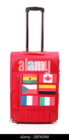 Roter Koffer mit vielen Aufklebern mit Flaggen verschiedener Länder isoliert auf weiß Stockfoto