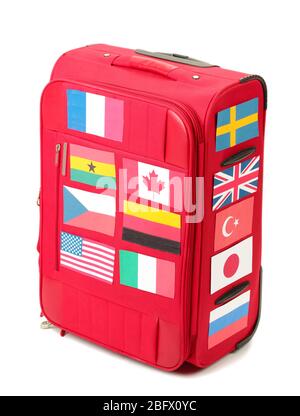 Roter Koffer mit vielen Aufklebern mit Flaggen verschiedener Länder isoliert auf weiß Stockfoto