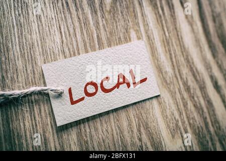 LOKALE handgeschriebene Papier Geschenkbox Etikett auf braunem Holz Textur Hintergrund , für den Kauf lokal kleine Wirtschaft. Stockfoto