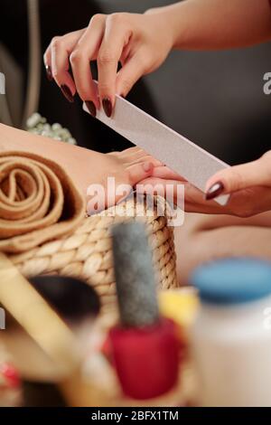 Pedicurist Feilen Fußnägel von weiblichen Kunden im Spa-Salon Stockfoto