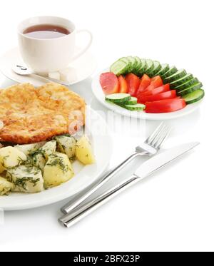 Gebratenes Hähnchenschnitzel mit gekochten Kartoffeln und Gemüse, Tasse Tee, auf weiß isoliert Stockfoto