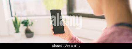 Frau mit Handy zu Hause bleiben Videos online auf 5g Daten App ansehen Blick von hinten mit schwarzen leeren Bildschirm Panorama-Banner Lifestyle. Stockfoto