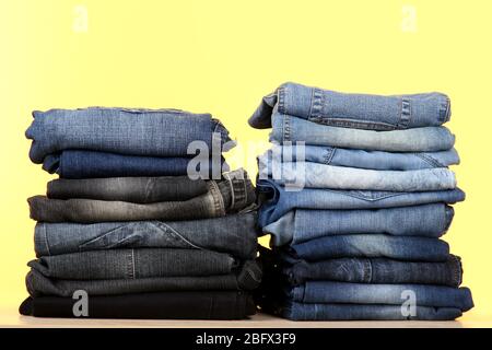 Viele Jeans in einem Stapel auf gelbem Hintergrund gestapelt Stockfoto