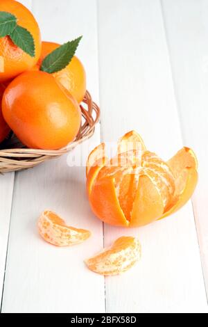 Mandarinen mit Blättern in einem schönen Korb, auf weißem Holztisch Stockfoto