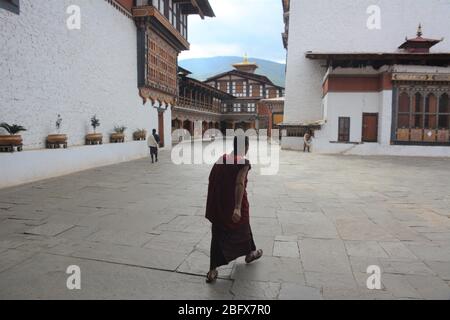 Ein junger Mönch spaziert in Rinpung Dzong, dem Hauptkloster und der Festung in Paro, Bhutan, das aus dem Jahr 1645 stammt und 14 Schreine und Kapellen enthält. Stockfoto