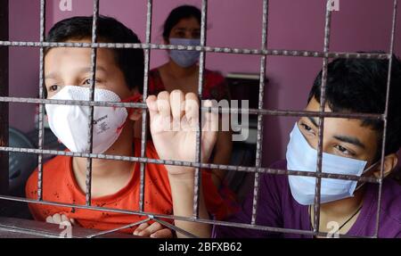 Besorgte und beängstigende Familie mit schützender Gesichtsmaske, die die verlassenen Straßen durch sein Zimmerfenster beobachtet - wegen Covit19 Coronavirus Pandem Stockfoto