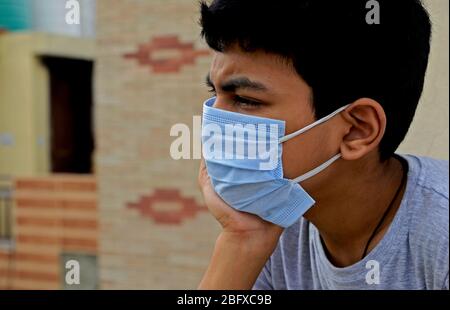 Besorgtes und besorgtes Kind mit schützender Gesichtsmaske, das die verlassenen Straßen in Indien beobachtet - wegen Covit19 Coronavirus-Pandemie. Sein Land (I Stockfoto