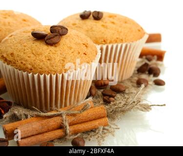 Leckere Muffin-Kuchen auf Burlap, Gewürze und Kaffeesamen, isoliert auf weiß Stockfoto