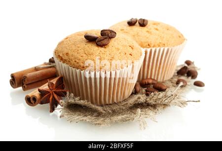 Leckere Muffin-Kuchen auf Burlap, Gewürze und Kaffeesamen, isoliert auf weiß Stockfoto