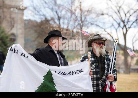 Helena, Montana - 19. April 2020: Zwei Männer stehen vor dem Kapitolgebäude bei einem Protest gegen die Wiedereröffnung des Staates wegen der Regierungsabschaltung für C Stockfoto