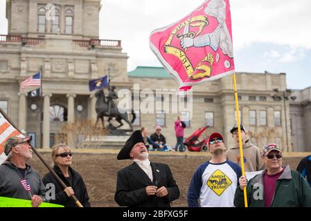 Helena, Montana - 19. April 2020: Demonstranten halten amerikanische Flaggen und blicken auf die Bedford-Miliz-Flagge bei einer Kundgebung, die das Geschäft wieder eröffnen will Stockfoto